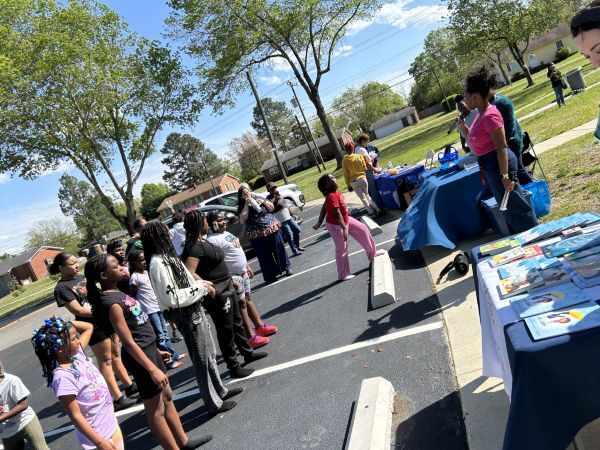 Children standing in a line listening to a speaker.