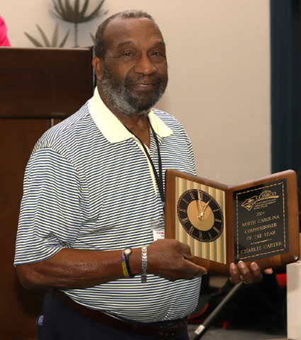 Charles Carter smiling and holding the Commissioner of the Year award.