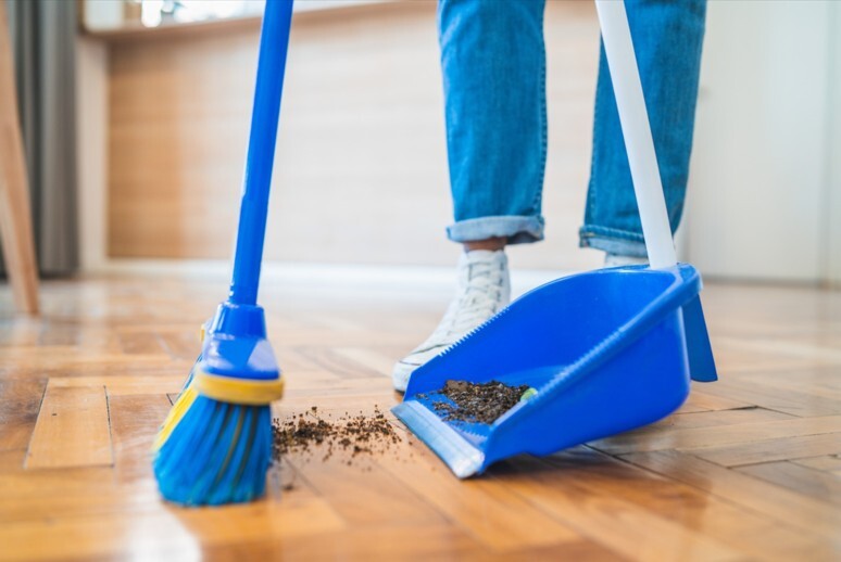 A broom sweeping dirt into a dustpan.
