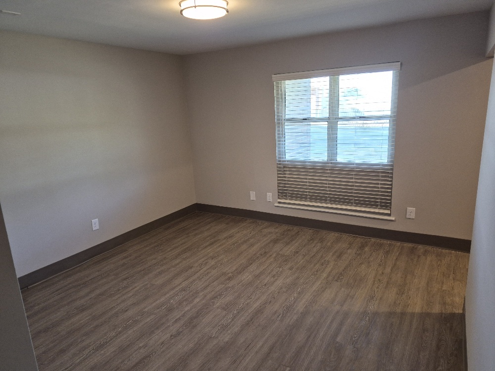 An empty bedroom with a large window.