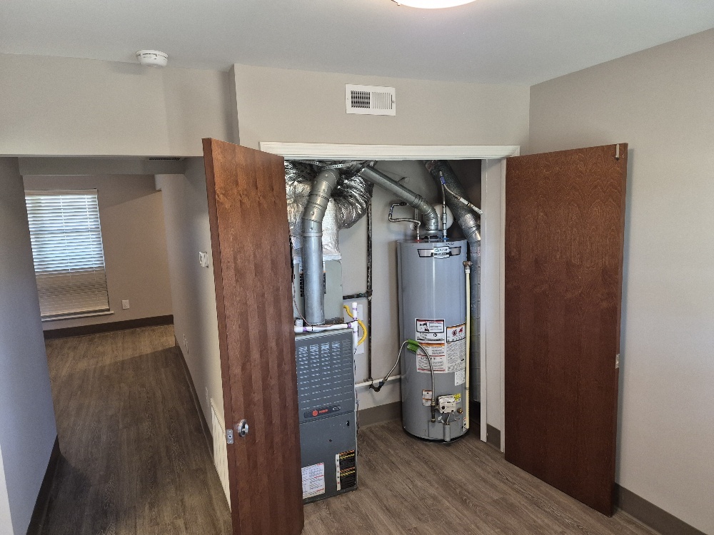 An open utility closet on the right, with a hall leading into another room on the left.