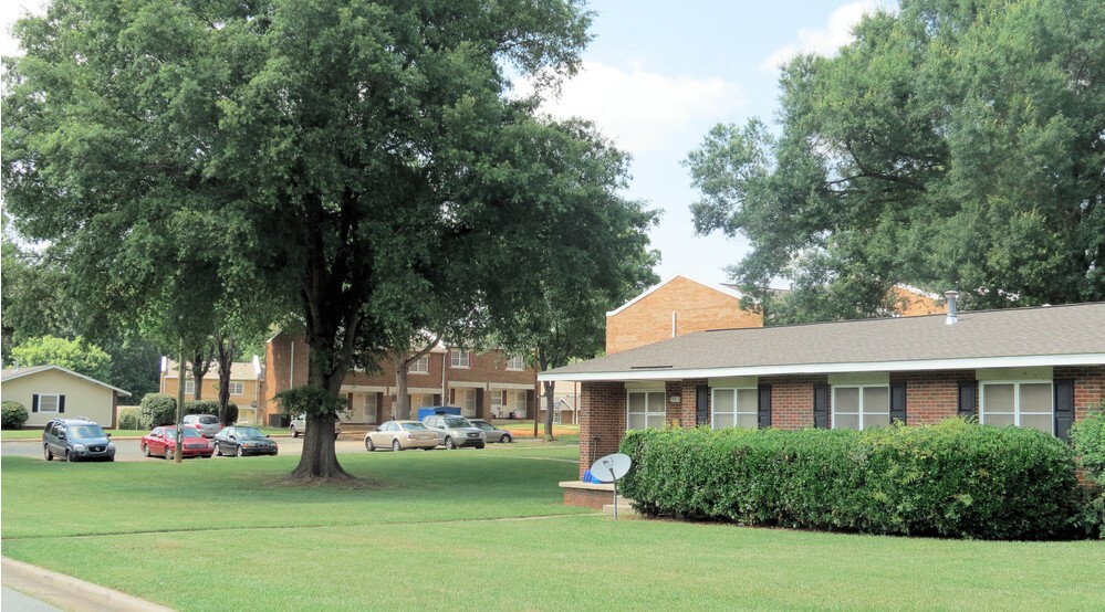 A big grass lawn with a brick house in the background.