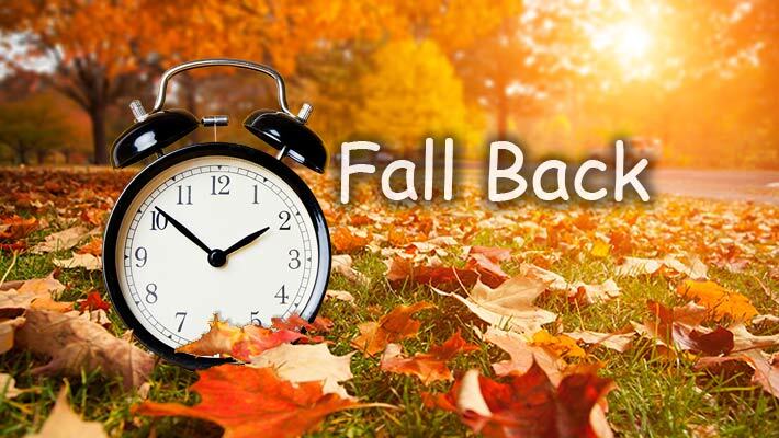 Fall leaves with an alarm clock and the words Fall Back.