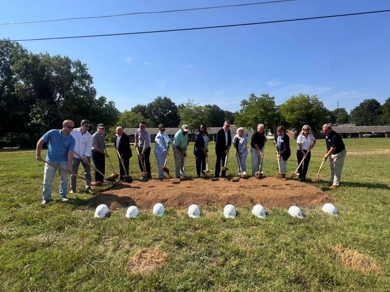 Fourteen people holding shovels and digging up dirt from a pile at the HOPE Village groundbreaking ceremony.