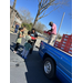  A man standing in the bed of a truck handing a box of fresh fruit to four people. 