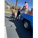  A man handing a box of fresh fruit to 2 people. 