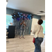  A male teen poses infront of a sparkly background with multi colored balloons. 