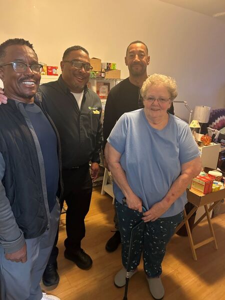 A woman smiling with three men for a picture.