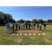  Fourteen people in a field with shovels, shoveling dirt together. 